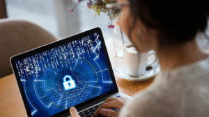 Person using a laptop with a digital lock symbol and binary code, representing cybersecurity and protection against modern-day hackers.